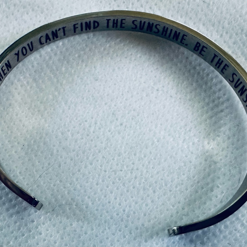 Silver tone cuff bracelet with inspiration message on inside.